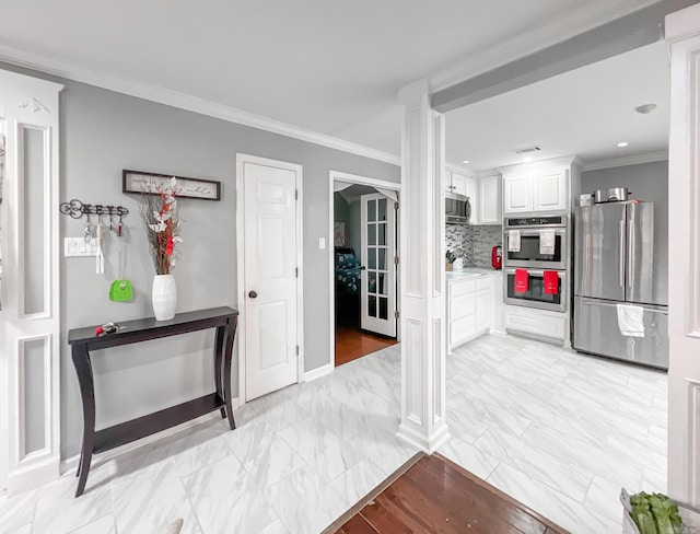 kitchen with backsplash, crown molding, ornate columns, white cabinetry, and stainless steel appliances