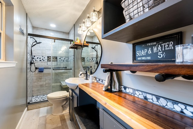 bathroom with toilet, vanity, wood-type flooring, and walk in shower