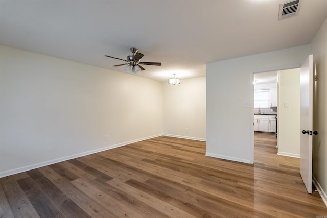 unfurnished room featuring ceiling fan, sink, and hardwood / wood-style flooring