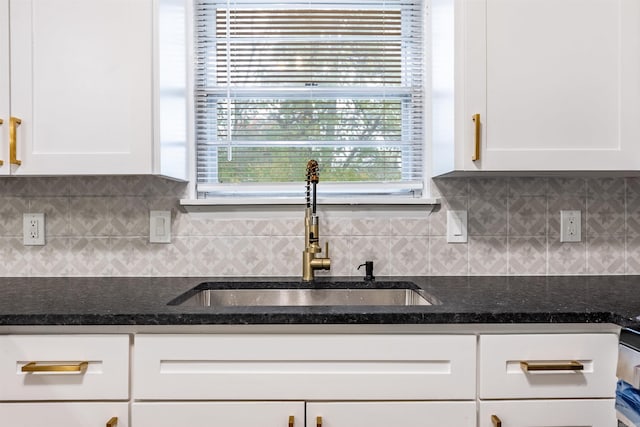 kitchen featuring white cabinets, backsplash, and sink