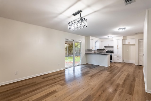 kitchen featuring white cabinetry, kitchen peninsula, light hardwood / wood-style floors, decorative light fixtures, and stainless steel stove