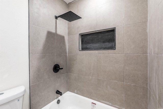 bathroom featuring tiled shower / bath combo and toilet