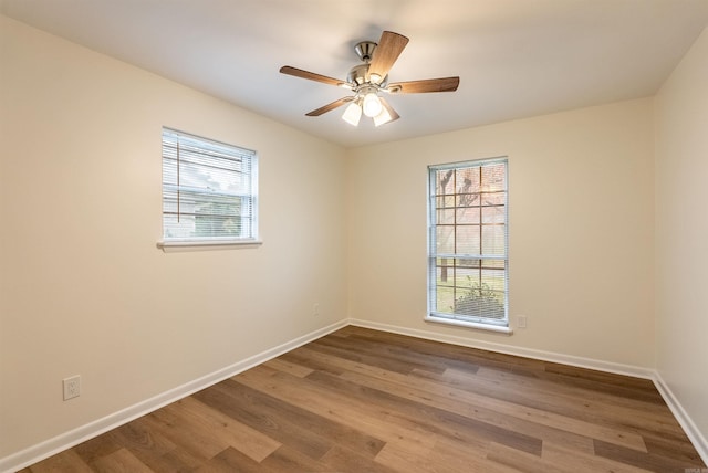 empty room featuring plenty of natural light, ceiling fan, and wood-type flooring