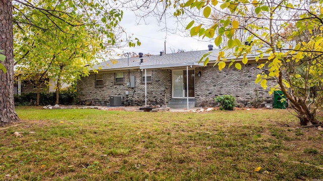 rear view of house with central AC and a lawn