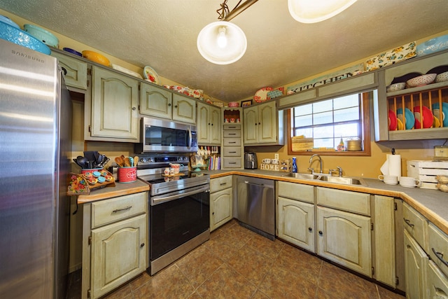 kitchen with decorative light fixtures, a textured ceiling, stainless steel appliances, and sink