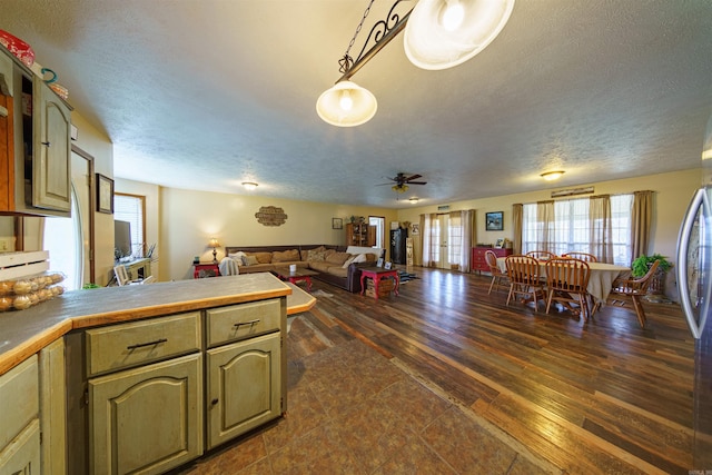 kitchen with ceiling fan, dark hardwood / wood-style flooring, hanging light fixtures, and a textured ceiling