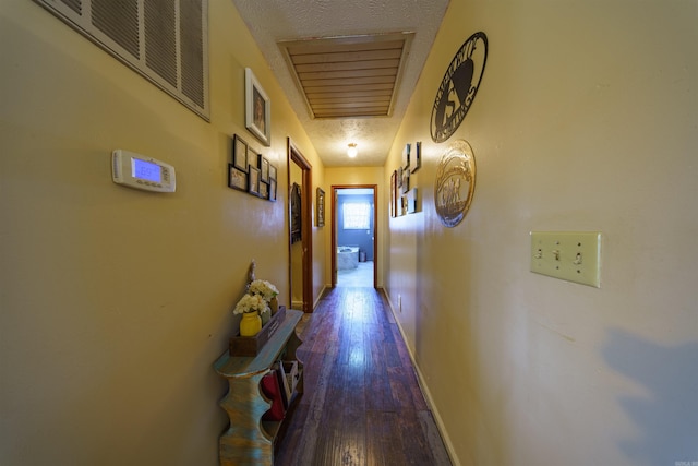 hall with a textured ceiling and dark wood-type flooring