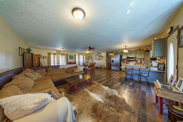 living room featuring a textured ceiling, dark hardwood / wood-style flooring, and ceiling fan