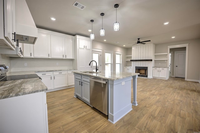 kitchen featuring stainless steel dishwasher, sink, decorative light fixtures, a center island with sink, and white cabinets