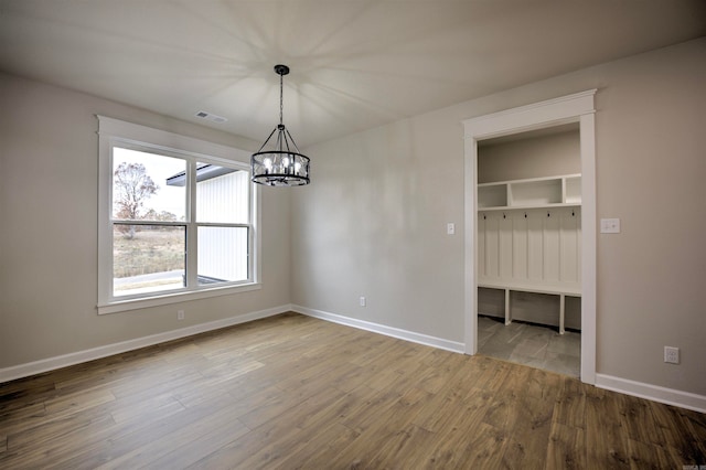 unfurnished dining area with a chandelier and wood-type flooring