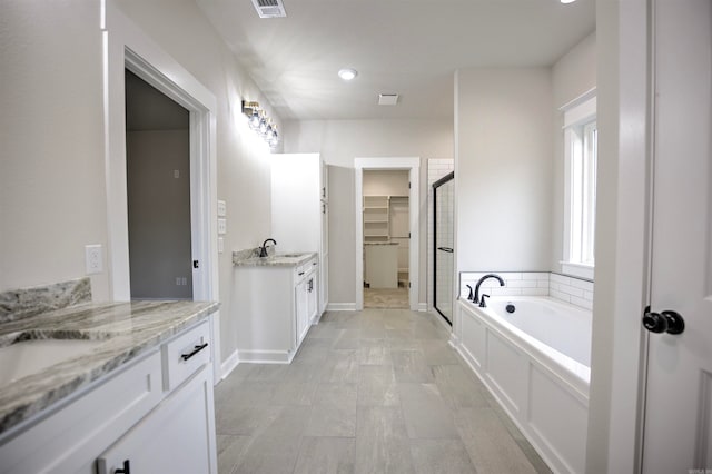 bathroom featuring vanity and independent shower and bath