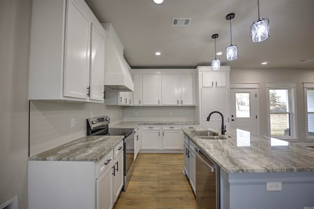 kitchen featuring stainless steel appliances, sink, a center island with sink, white cabinetry, and hanging light fixtures