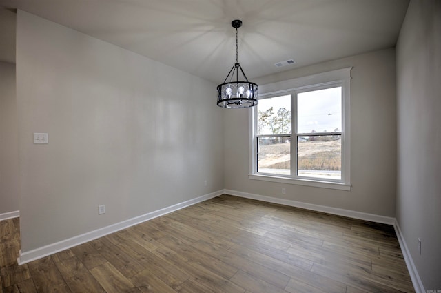 unfurnished dining area featuring hardwood / wood-style flooring and an inviting chandelier