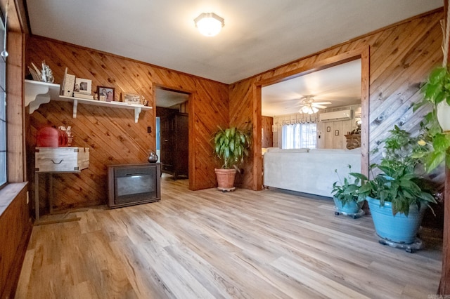 interior space with light hardwood / wood-style flooring, ceiling fan, an AC wall unit, and wood walls