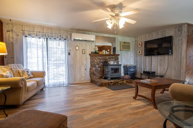 living room with a wood stove, wood walls, hardwood / wood-style floors, and a wall mounted AC