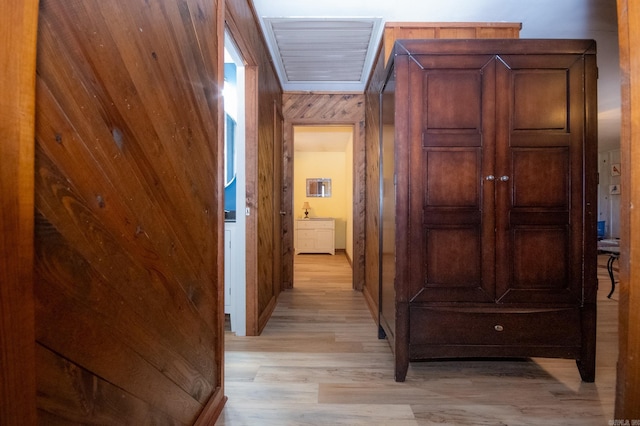 hallway with wooden walls and light hardwood / wood-style flooring