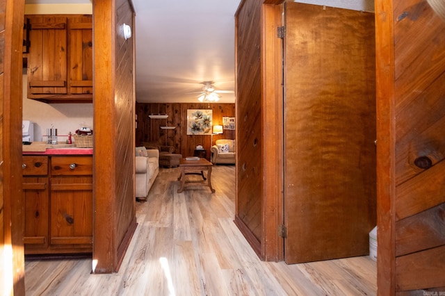 hall with light hardwood / wood-style flooring and wood walls