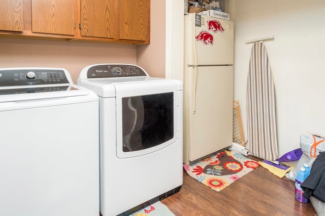 clothes washing area featuring cabinets, wood-type flooring, and independent washer and dryer