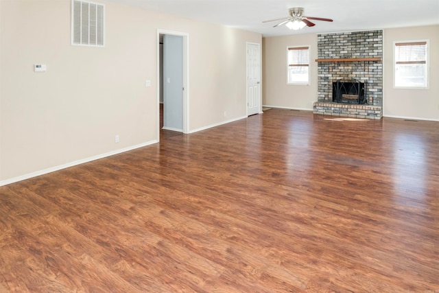 unfurnished living room featuring dark hardwood / wood-style floors, ceiling fan, and a brick fireplace