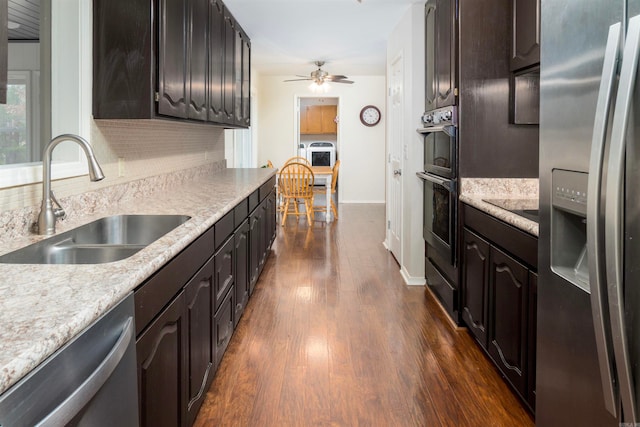 kitchen with dark wood-type flooring, sink, ceiling fan, appliances with stainless steel finishes, and dark brown cabinetry