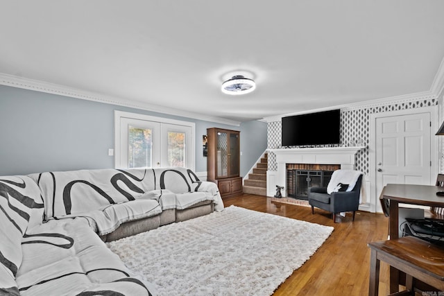 living room with wood-type flooring, crown molding, and a brick fireplace