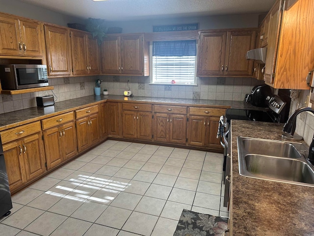 kitchen with range hood, light tile patterned floors, sink, and appliances with stainless steel finishes