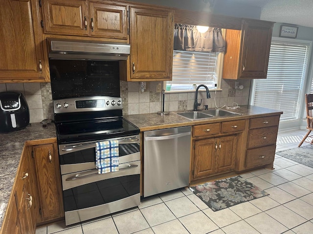 kitchen with sink, decorative backsplash, light tile patterned floors, and stainless steel appliances