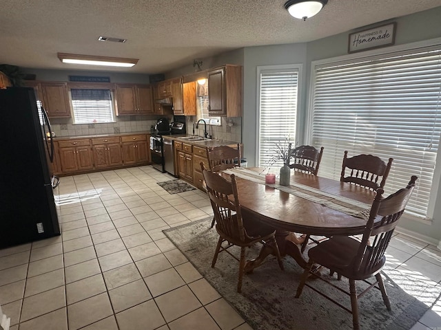 dining space with light tile patterned flooring, a healthy amount of sunlight, and a textured ceiling