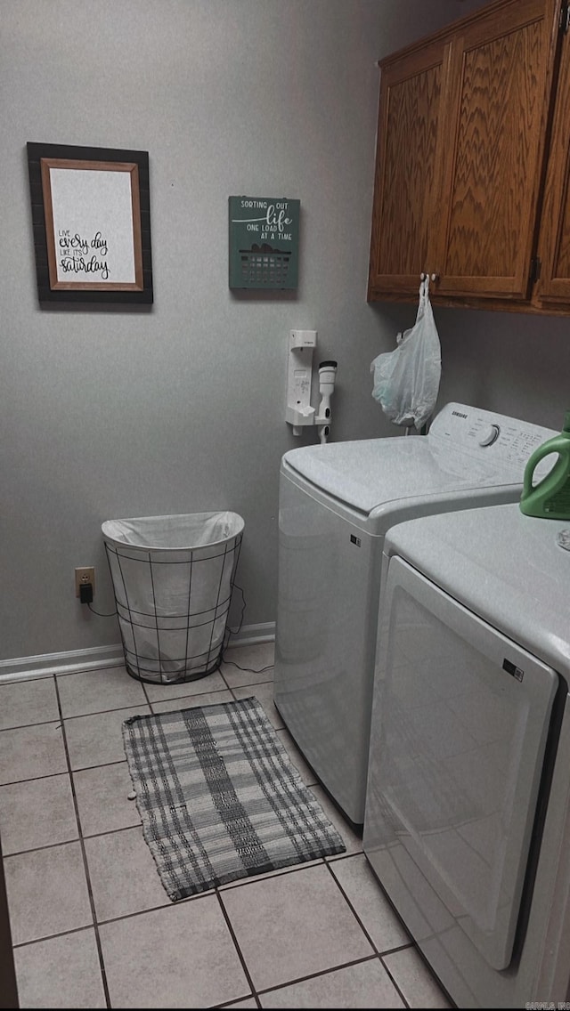 clothes washing area featuring light tile patterned flooring, cabinets, and washer and clothes dryer