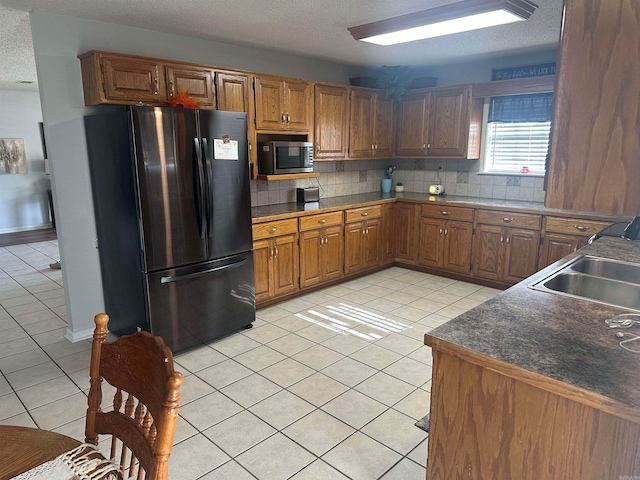 kitchen with sink, light tile patterned flooring, a textured ceiling, decorative backsplash, and stainless steel appliances