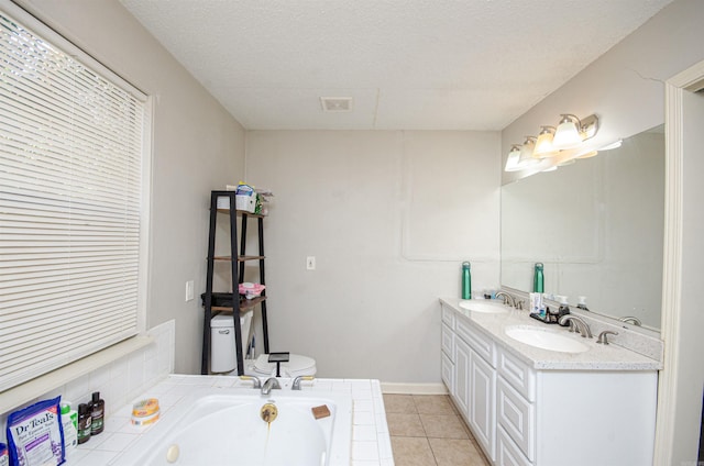 bathroom with vanity, tile patterned flooring, toilet, a textured ceiling, and a tub