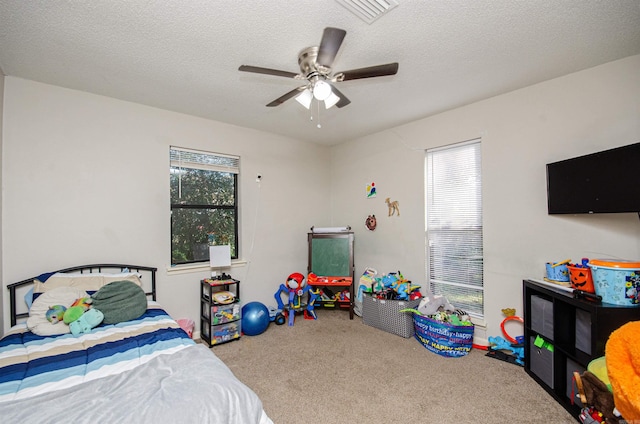 carpeted bedroom featuring ceiling fan and a textured ceiling