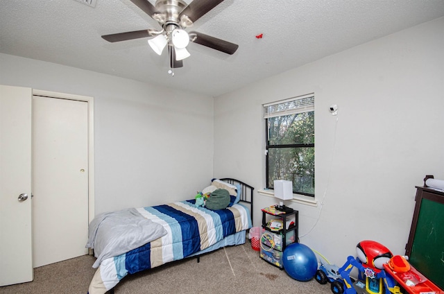 carpeted bedroom with ceiling fan and a textured ceiling