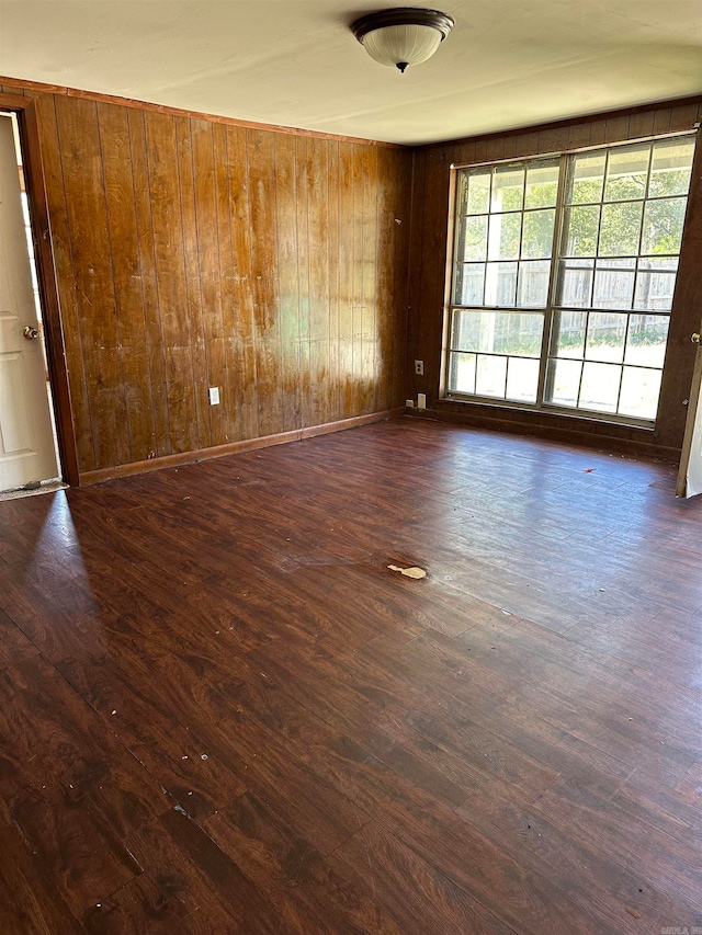 spare room featuring wood walls and dark hardwood / wood-style floors