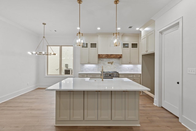 kitchen featuring hanging light fixtures, crown molding, an island with sink, and high end stainless steel range