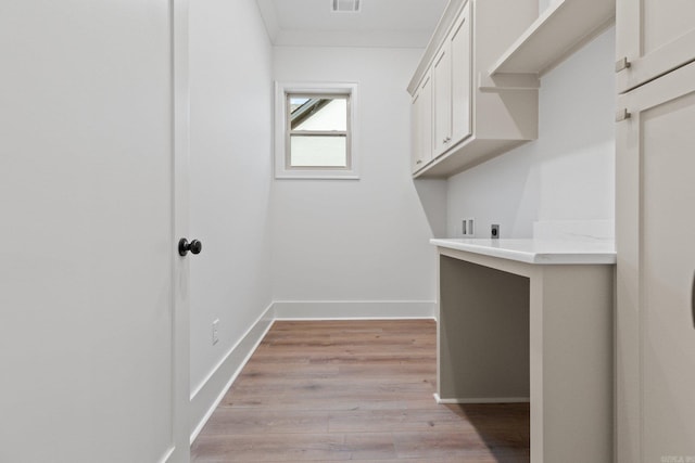 washroom with electric dryer hookup, cabinets, and light wood-type flooring