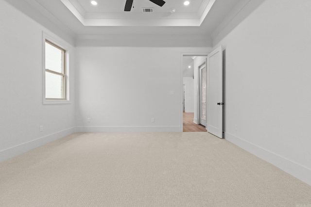 carpeted empty room with a tray ceiling, ceiling fan, and crown molding