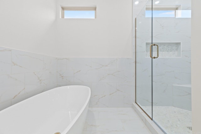 bathroom featuring shower with separate bathtub and tile walls