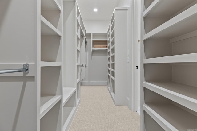 walk in closet with light carpet