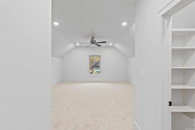 bonus room featuring built in shelves, ceiling fan, light colored carpet, and vaulted ceiling