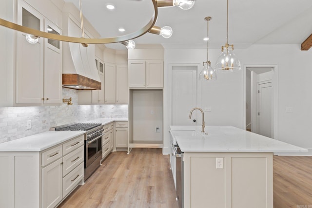 kitchen featuring white cabinets, sink, light wood-type flooring, decorative light fixtures, and stainless steel appliances