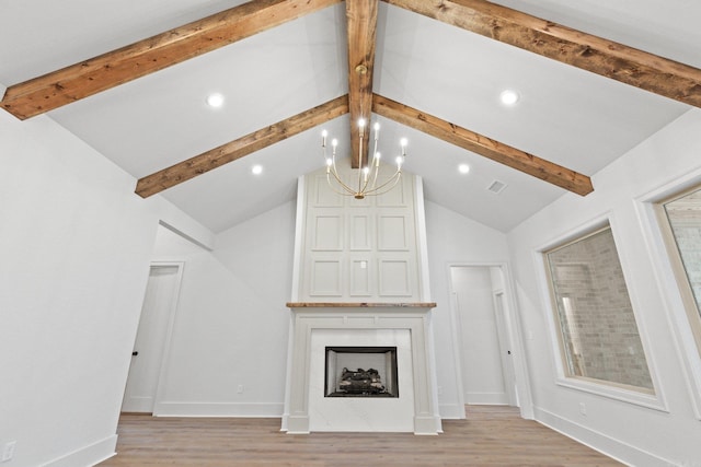 unfurnished living room featuring vaulted ceiling with beams, a large fireplace, light hardwood / wood-style flooring, and an inviting chandelier