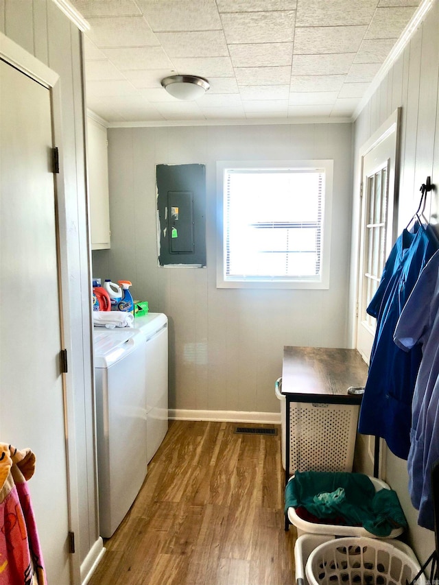 laundry room with hardwood / wood-style floors, cabinets, electric panel, separate washer and dryer, and ornamental molding