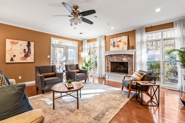 living room featuring a fireplace, light hardwood / wood-style floors, a wealth of natural light, and crown molding