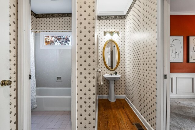 bathroom featuring hardwood / wood-style flooring, ornamental molding, and bathtub / shower combination