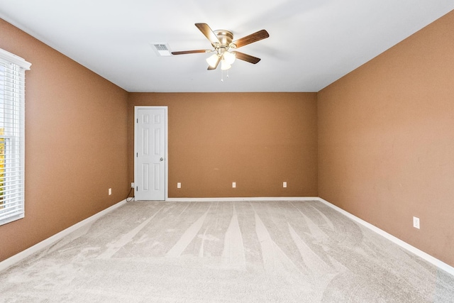 spare room featuring ceiling fan, light colored carpet, and a healthy amount of sunlight