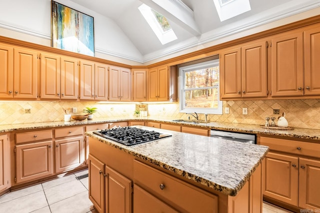 kitchen featuring vaulted ceiling with skylight, stainless steel appliances, sink, light tile patterned floors, and a kitchen island