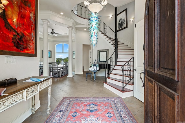 tiled entryway with ceiling fan, crown molding, and decorative columns