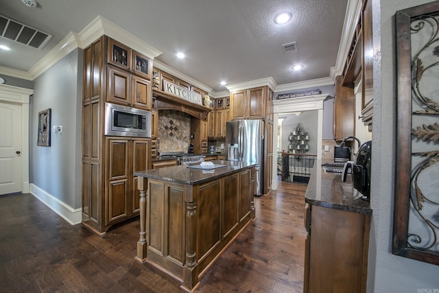 kitchen with dark stone countertops, a center island, dark hardwood / wood-style flooring, and appliances with stainless steel finishes