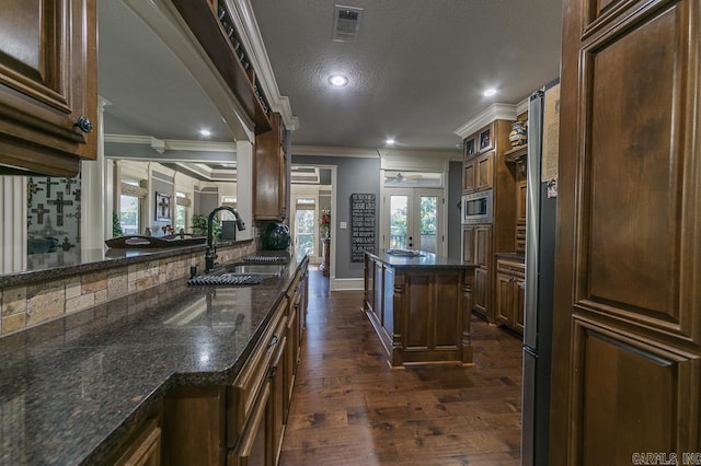 kitchen featuring stainless steel microwave, sink, dark hardwood / wood-style flooring, dark stone countertops, and ornamental molding